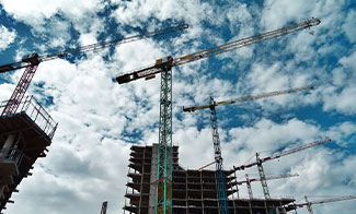 construction cranes with buildings-against blue sky with clouds