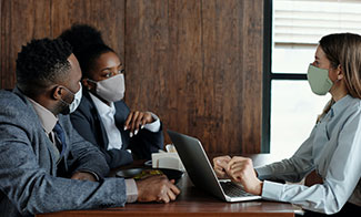 office workers in facemasks-meeting-with-woman in facemask with laptop