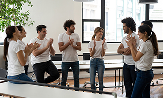 group in matching white-t-shirts applauding co-worker