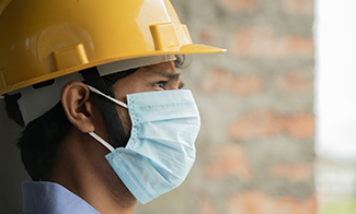 Close-up-side-view-of-man-in-hard-hat-and-Covid-face-mask