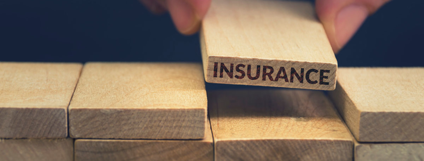 close-up-of-hand-holding-wooden-piece-of-wall-that-says-insurance