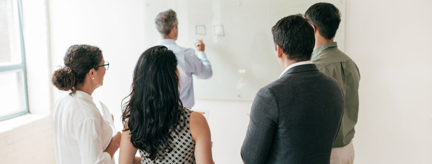 4-people-standing-around-lecturer-writing-on-white-board