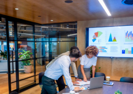 3-people-standing-around-laptop-in-conference-room